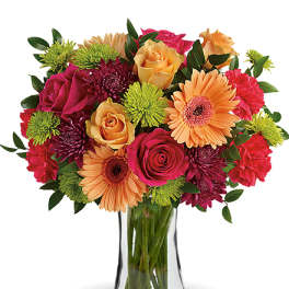Mixed bouquet of roses, gerbera daisies, and chrysanthemums in a glass vase
