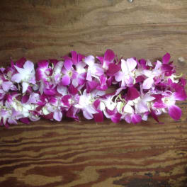 Two garlands of pink and white orchid blossoms on a wooden surface