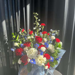 Bouquet of red, white, and blue flowers wrapped in pale blue paper