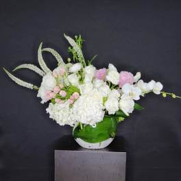White and pink floral arrangement in a round vase with long arching stems