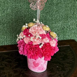 Pink flower arrangement in a heart container with a heart balloon and chocolates