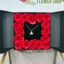 Box of red roses with a necklace in the center