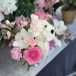 Pink and white bouquet with roses and orchids tied with a ribbon
