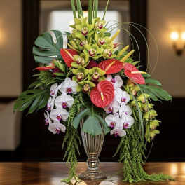 Tropical flower arrangement with orchids and red anthuriums in a glass vase