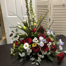Mixed bouquet with red roses, white tulips, and daisies around a birdhouse