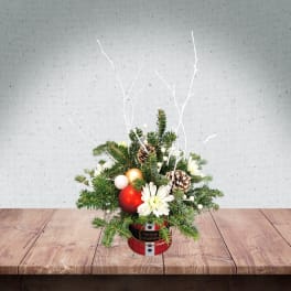 Christmas arrangement with pine, white flowers, and ornaments in a red tin container
