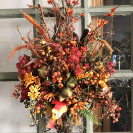 Autumn floral arrangement with orange blooms and berries on a door