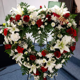 Heart-shaped floral wreath with white lilies, red roses, and white daisies