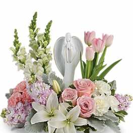 Pink roses and white lilies arranged around a silver angel figurine