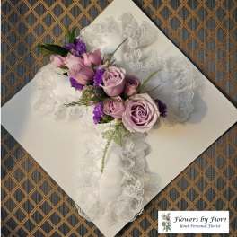 Lavender roses and purple flowers arranged on white lace ribbon