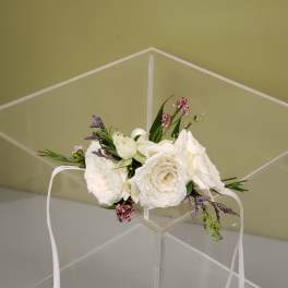 White floral crown with small pink and purple flowers on a clear stand