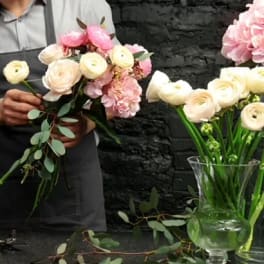 Florist holding a bouquet of pale pink and cream ranunculus