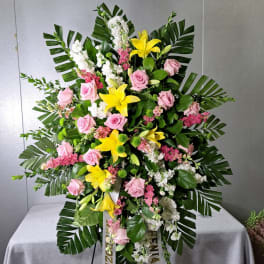 Standing floral spray with pink roses, yellow lilies, and white blooms