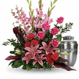 Pink and red floral funeral arrangement with a silver urn