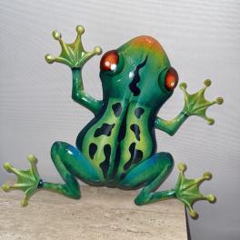 Colorful frog figurine with outstretched legs on a stone surface