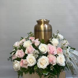 Pink and white roses arranged around a gold urn