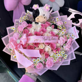 Pink and white rose bouquet with a plush cow and birthday ribbon