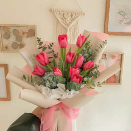 Pink tulip bouquet wrapped in cream paper with a pink ribbon