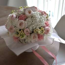 Round bouquet of pale pink and white flowers wrapped in paper