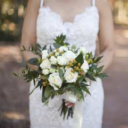 Bride holding a white rose bouquet with greenery
