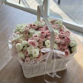 Basket of pink and white roses with a ribbon handle