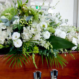 Large white floral spray arranged on a wooden casket