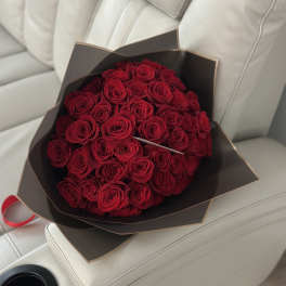 Bouquet of red roses wrapped in dark paper