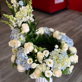 White and blue floral arrangement with roses and hydrangeas in a vase