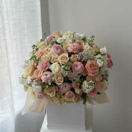 Large pastel bouquet of roses, ranunculus, and carnations in a white box