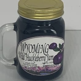 Dark jar candle with a gold lid and handle, labeled Wyoming Wild Huckleberry Jam.
