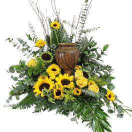 Sunflower and yellow rose arrangement around a brown urn