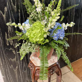 Potted floral arrangement with blue hydrangeas, green blooms, and white snapdragons
