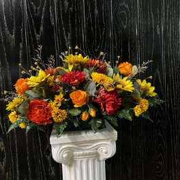 Bright orange and yellow floral arrangement on a white pedestal