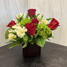 Red roses and white alstroemeria in a dark glass vase