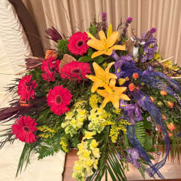 Large mixed floral arrangement with lilies, gerbera daisies, and purple accents