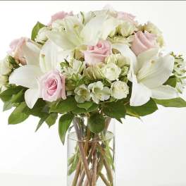 Pink roses and white lilies arranged in a clear glass vase