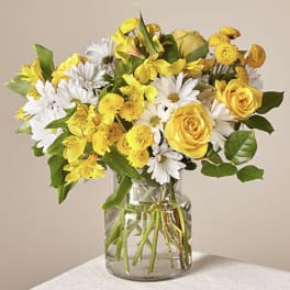 Yellow roses and white daisies in a clear glass vase