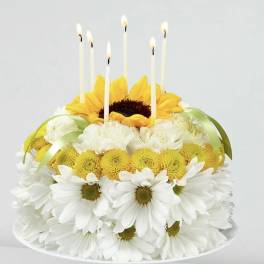 Flower cake with candles and white daisies on a pedestal stand