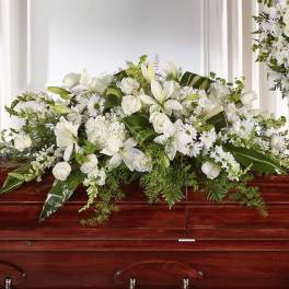 White floral casket spray with lilies, roses, and daisies