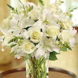 White lilies and roses arranged in a clear glass vase