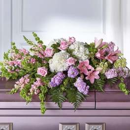 Pink and white floral casket spray with lilies, roses, and hydrangeas