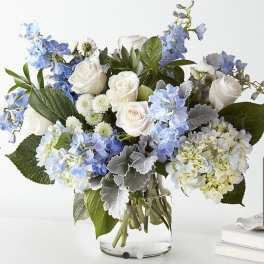 Blue and white flower arrangement in a clear glass vase