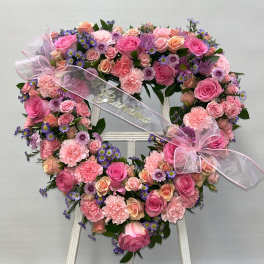 Heart-shaped floral wreath with pink roses, carnations, and purple daisies