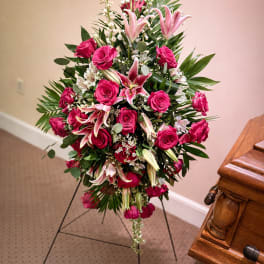 Standing floral spray with pink roses and lilies on a black easel