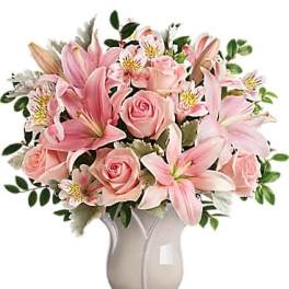 Pink lilies and roses arranged in a ceramic vase