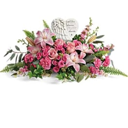 Pink lilies and roses arranged around a heart-shaped memorial plaque