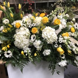 Large white and yellow floral casket spray with ribbon accents