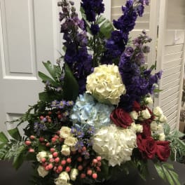 Tall mixed floral arrangement with purple, white, blue, and red blooms