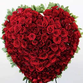 Heart-shaped arrangement of red roses with green foliage