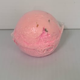 Pink spherical bath bomb wrapped in clear plastic